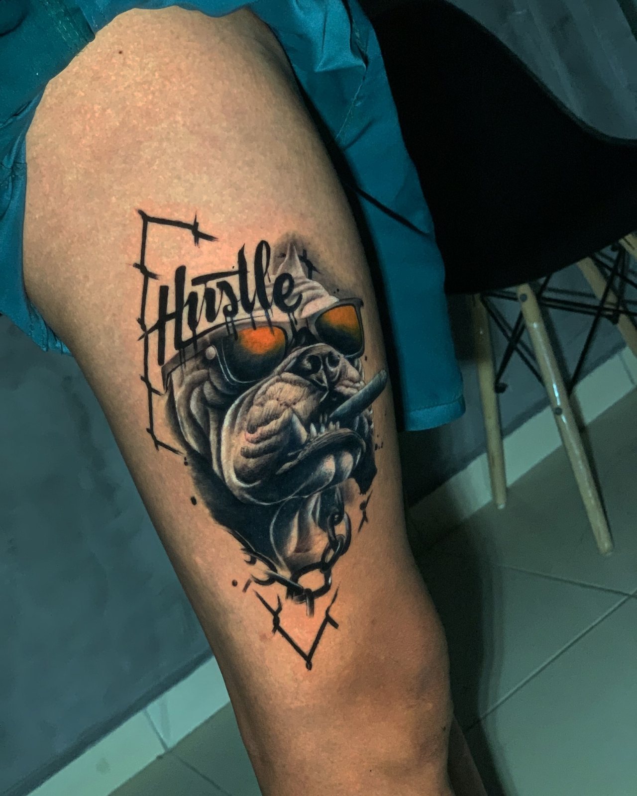 Tatuagem na coxa: bulldog de óculos com charuto e a palavra Hustle